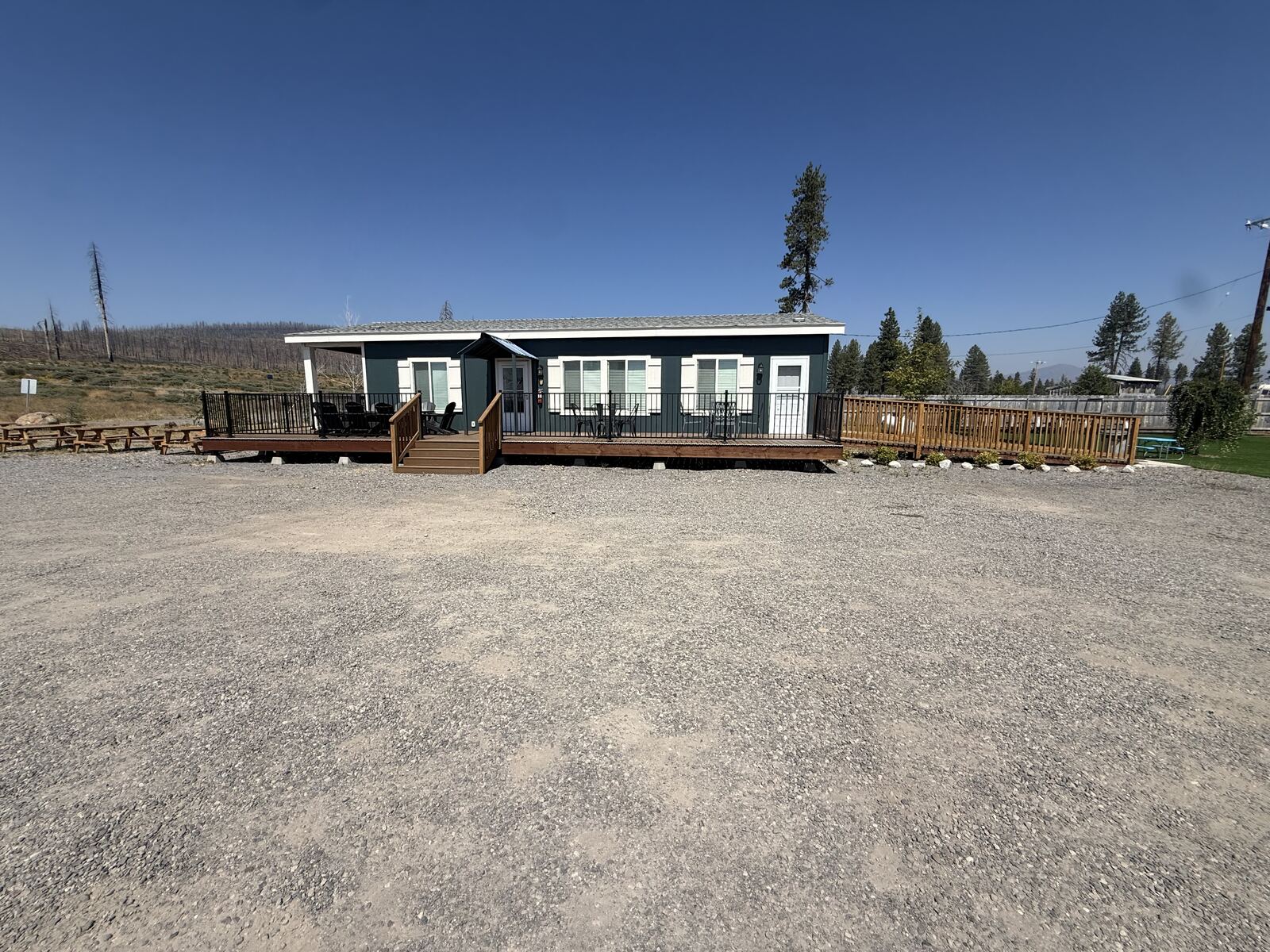 The house at Cedar Lodge seen head on, dark green boards with a long railed deck and steps.