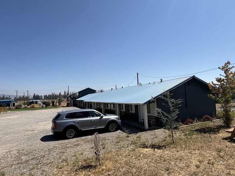 The motel row at Cedar Lodge under its metal roof, doors opening onto the covered walkway.